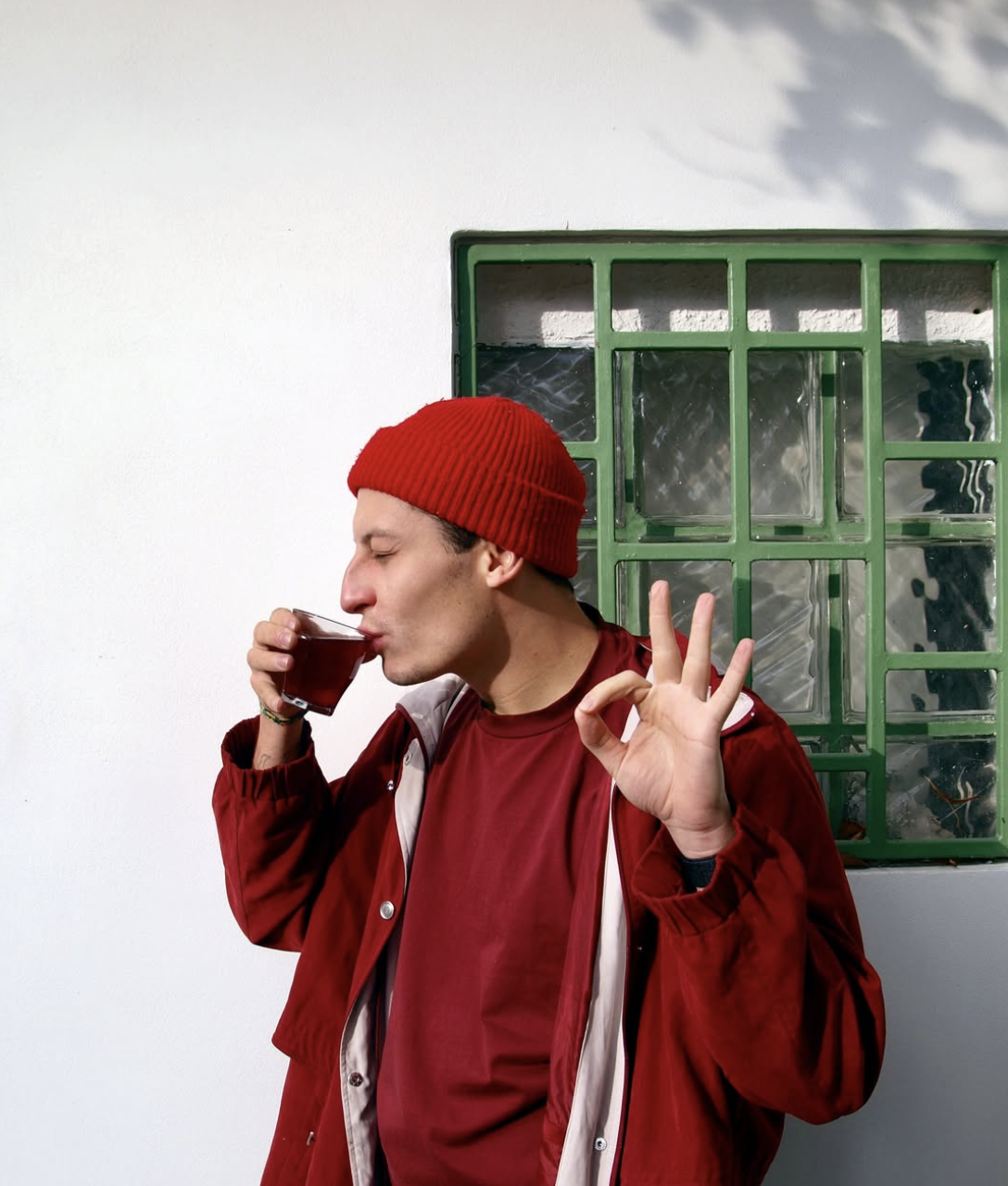 Návštěvník s červenou čepicí popíjí espresso před kavárnou